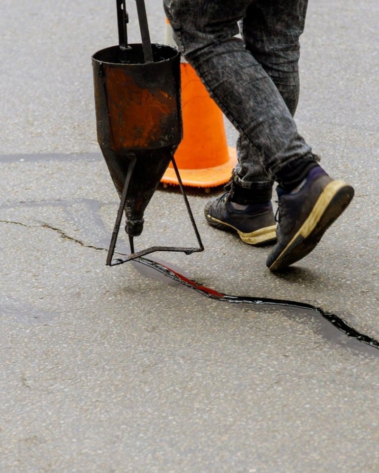 Sealing joint crack in asphalt road surface restoration work.